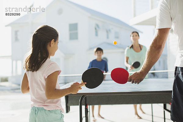 Familie beim gemeinsamen Tischtennisspielen im Freien