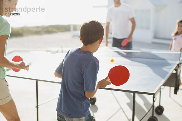 Familie beim gemeinsamen Tischtennisspielen im Freien