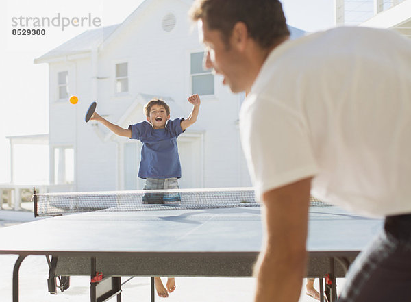 Vater und Sohn spielen Tischtennis im Freien