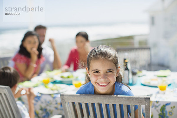 Lächelndes Mädchen am Tisch auf der Sonnenterrasse