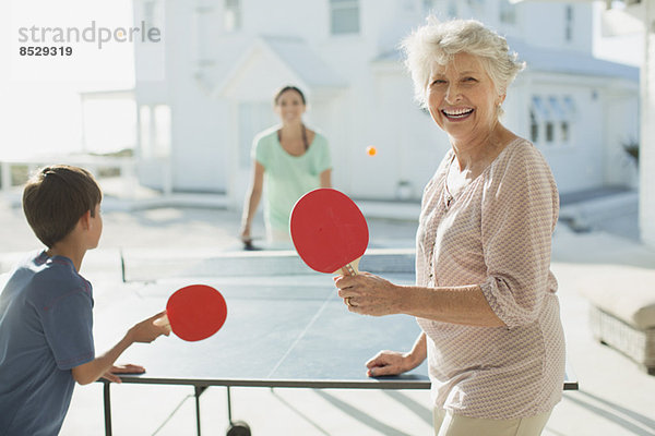 Mehrgenerationen-Familie beim Tischtennisspielen vor dem Strandhaus