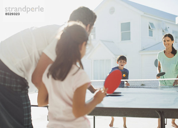 Familie spielt Tischtennis außerhalb des Hauses