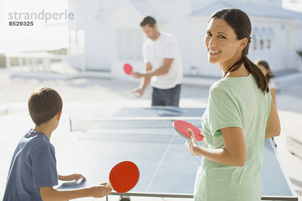 Familie beim gemeinsamen Tischtennisspielen im Freien