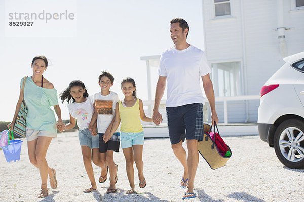 Familie beim Händchenhalten und Wandern mit Strandkleidung in sonniger Einfahrt