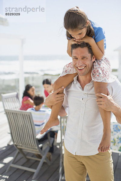 Vater trägt Tochter auf Schultern auf sonniger Terrasse