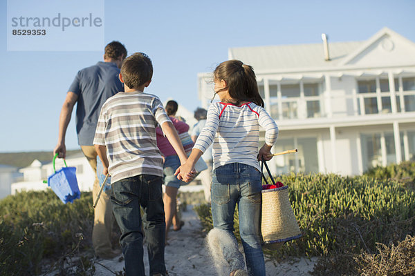 Bruder und Schwester halten sich am Strandweg an den Händen.