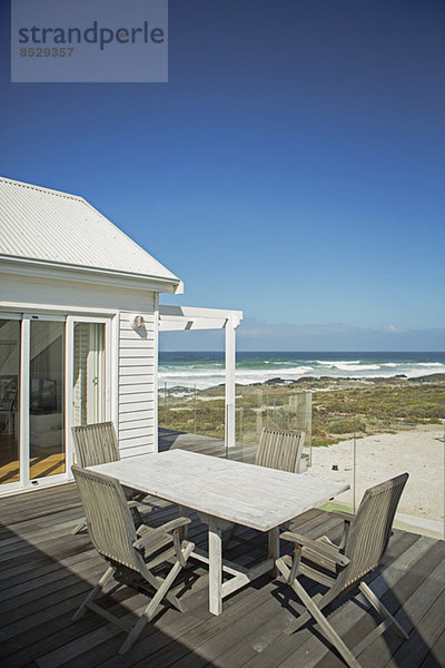Tisch und Stühle auf der Terrasse mit Blick auf den Strand