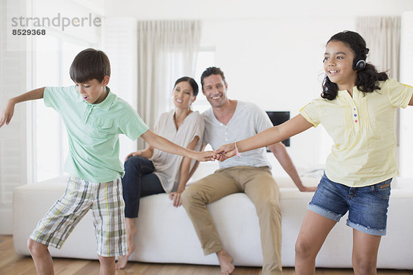 Eltern beobachten Tochter und Sohn beim Tanzen im Wohnzimmer