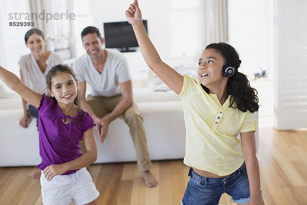 Eltern beobachten Töchter beim Tanzen im Wohnzimmer