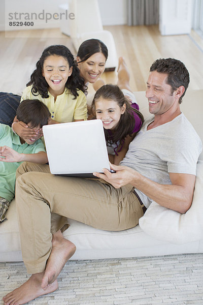 Familie mit Laptop auf Sofa im Wohnzimmer