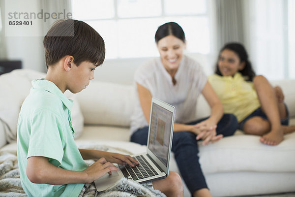 Junge mit Laptop auf Sofa im Wohnzimmer