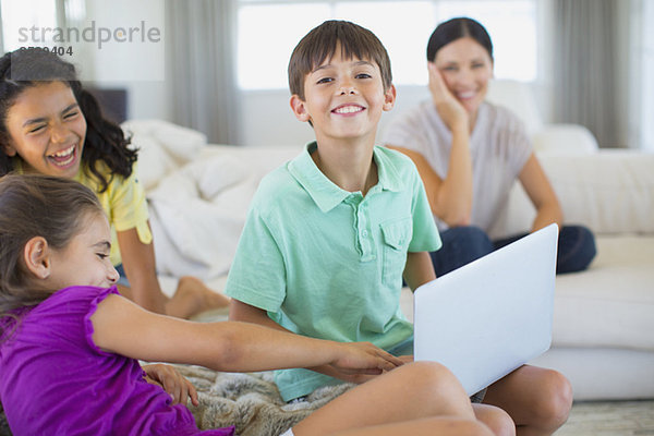 Familie mit Laptop auf Sofa im Wohnzimmer