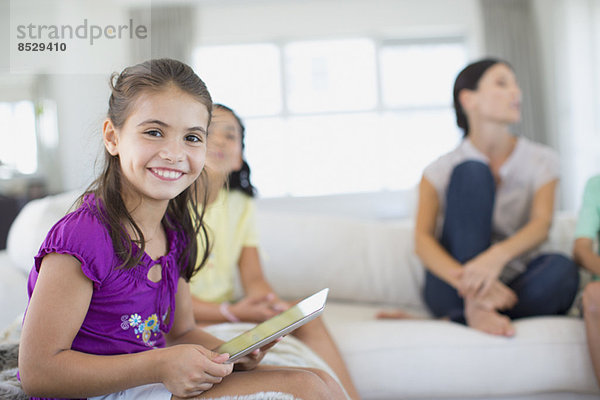 Mädchen mit digitalem Tablett auf Sofa im Wohnzimmer