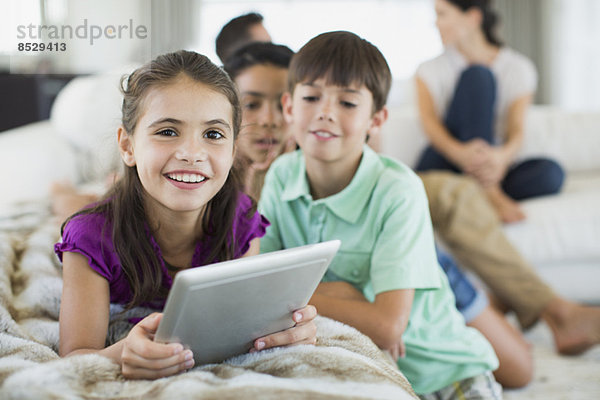 Kinder mit digitalem Tablett auf dem Sofa im Wohnzimmer