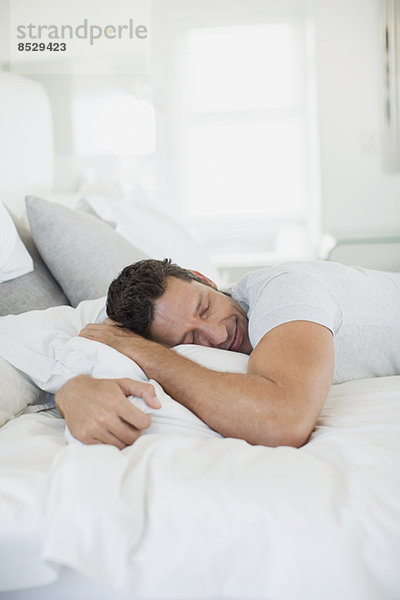 Mann umarmt Kissen auf Bett