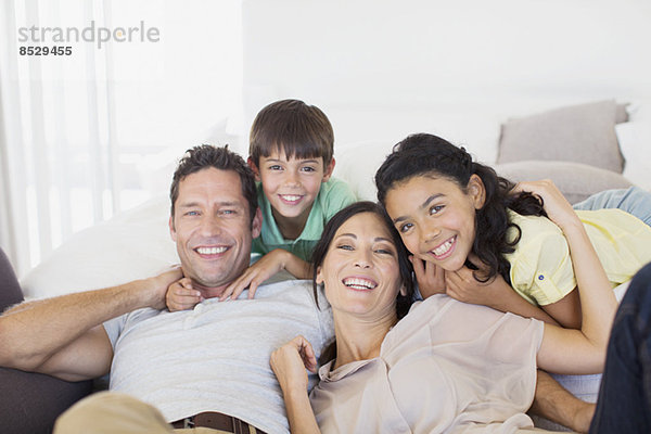 Familie lächelt gemeinsam auf dem Sofa im Wohnzimmer
