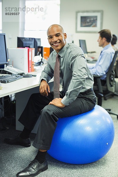 Geschäftsmann sitzend auf Fitnessball im Büro