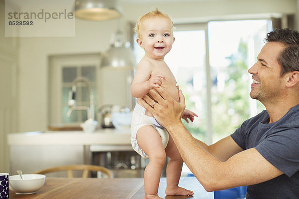 Vater hilft Baby auf dem Tisch gehen