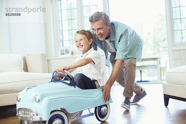 Vater schiebt Sohn im Spielzeugauto