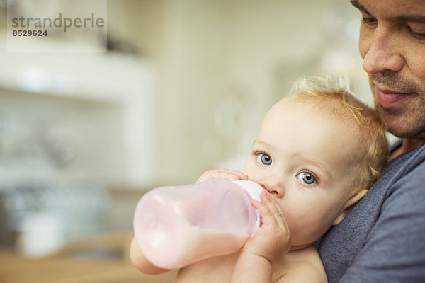 Vater füttert Baby in der Küche