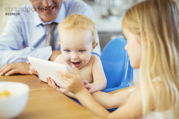 Mädchen zeigt Baby-Digital-Tablett am Tisch