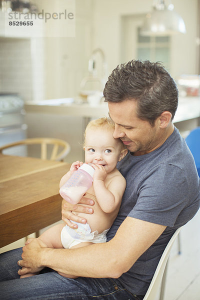 Vater füttert Baby in der Küche