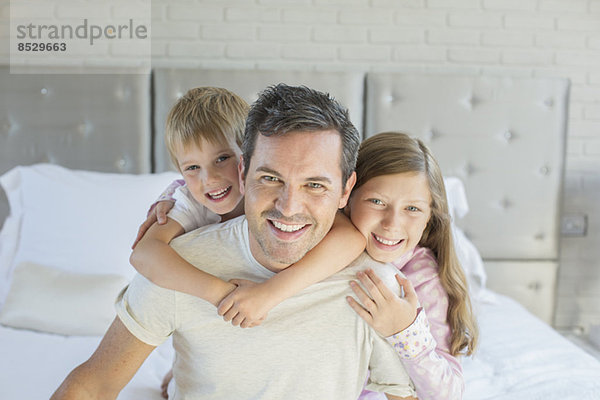 Vater und Kinder umarmen sich im Schlafzimmer