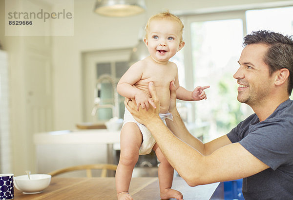 Vater hilft Baby auf dem Tisch gehen