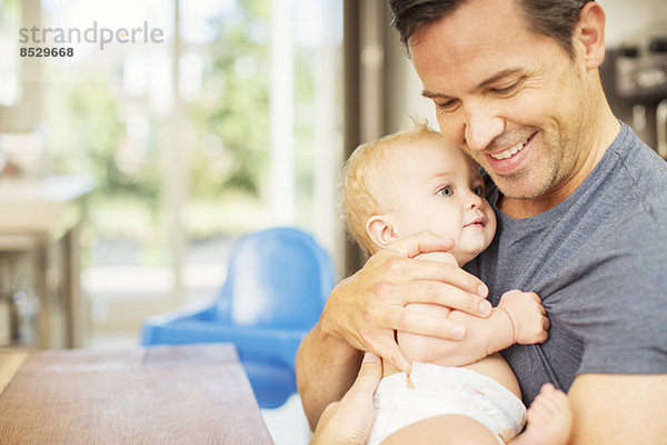 Vater hält Baby in der Küche