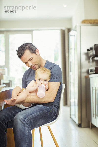 Vater füttert Baby in der Küche