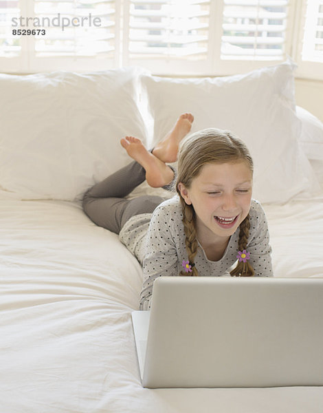 Mädchen mit Laptop im Bett