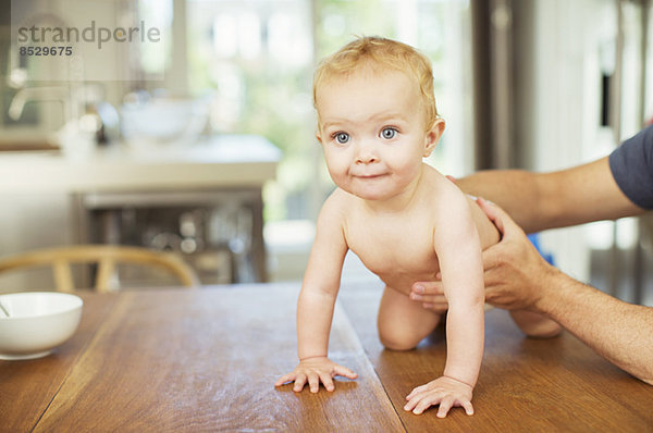 Vater hilft Baby auf dem Tisch krabbeln