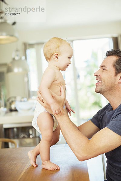 Vater hilft Baby auf dem Tisch gehen