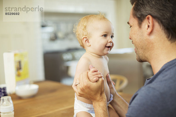 Vater hält Baby in der Küche