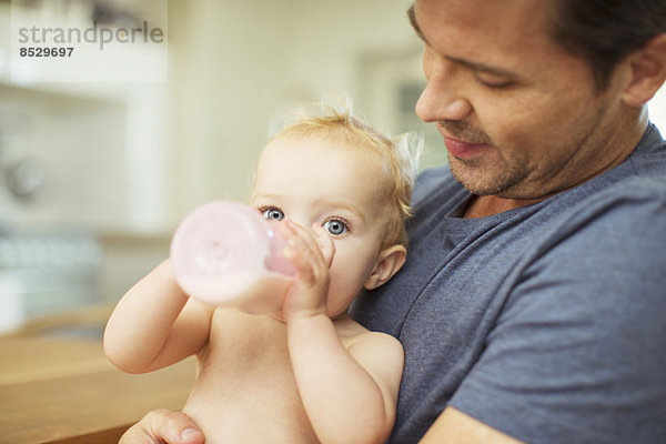 Vater füttert Baby in der Küche