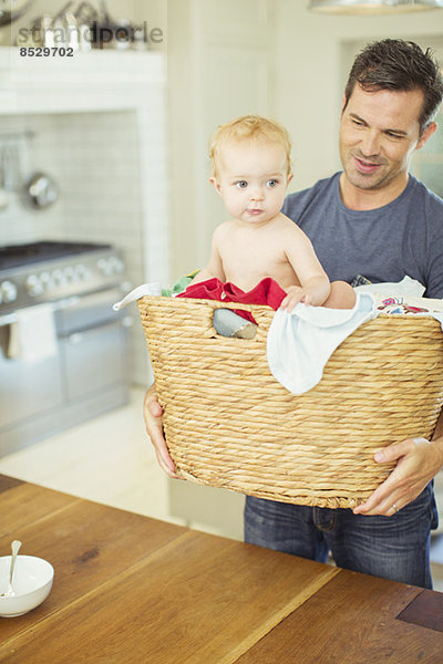 Vater trägt Baby im Wäschekorb