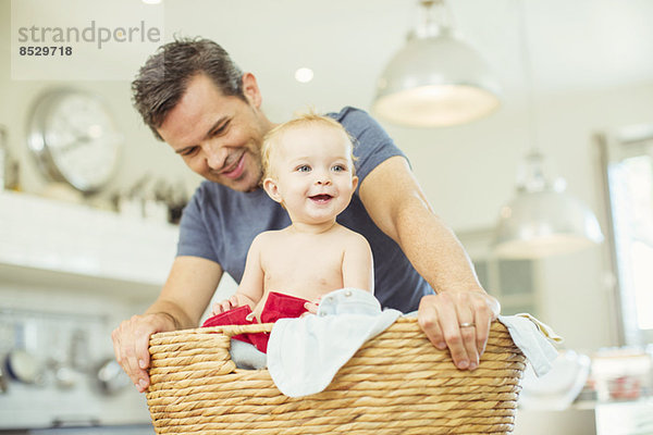 Vater trägt Baby im Wäschekorb