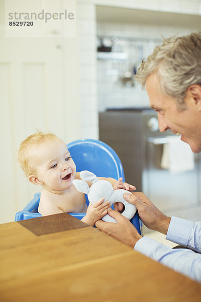 Vater spielt mit Baby im Hochstuhl