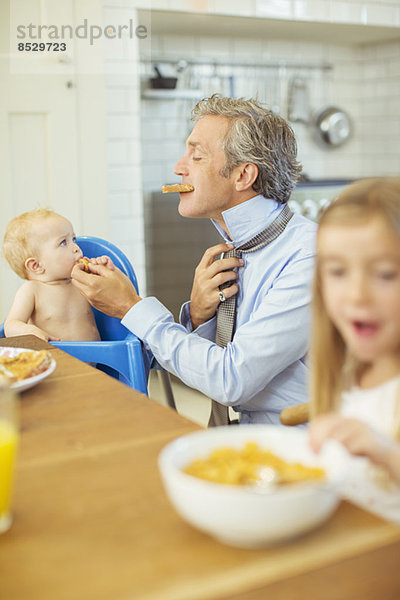 Vater und Kinder beim Frühstücken in der Küche
