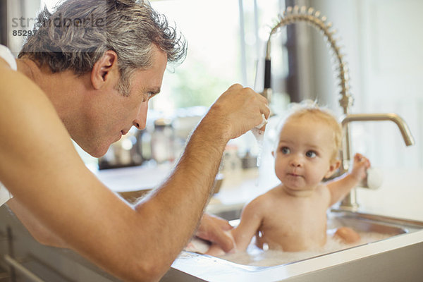 Vater badendes Baby in der Küchenspüle