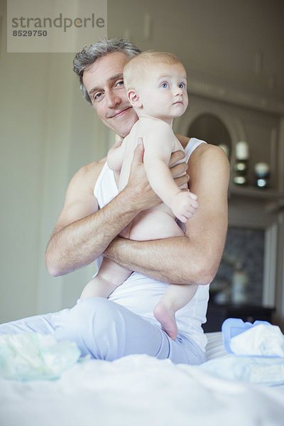 Vater hält Baby im Bett