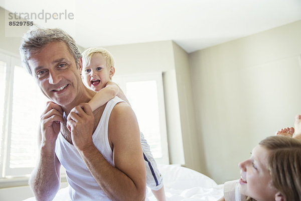 Vater und Kinder spielen auf dem Bett