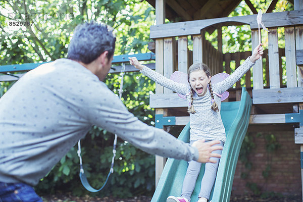 Vater fängt Tochter auf Rutsche