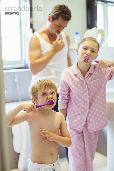 Vater und Kinder beim Zähneputzen im Bad