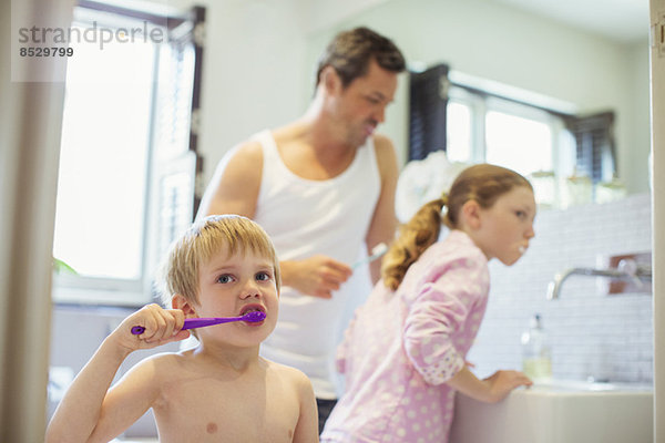 Vater und Kinder beim Zähneputzen im Bad