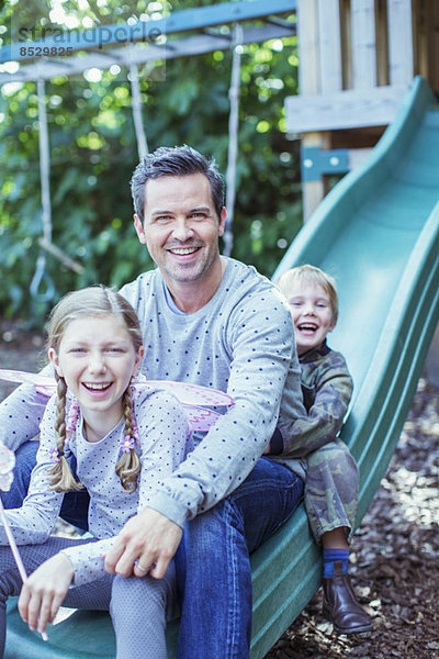 Vater und Kinder sitzen auf der Rutsche