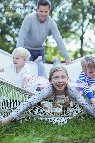 Vater schiebt Kinder in der Hängematte ins Freie