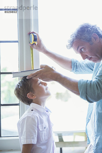 Vater misst die Höhe des Sohnes an der Wand