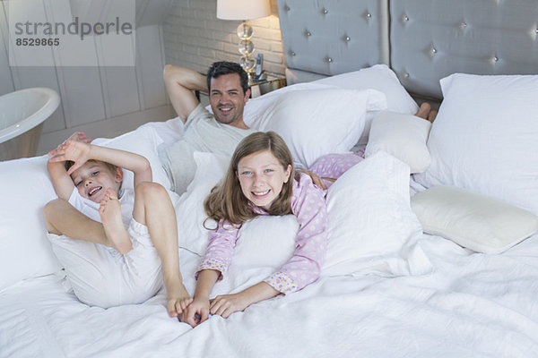 Vater und Kinder entspannen sich auf dem Bett
