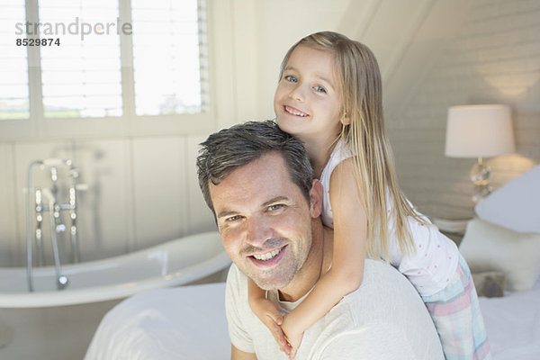 Vater und Tochter lächeln im Schlafzimmer